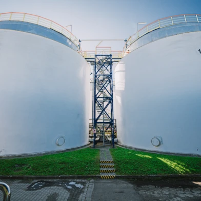 A steel storage tank, silo, and pipe in an industrial factory setting. Engineering marvels at play with cylinders and steel structures.